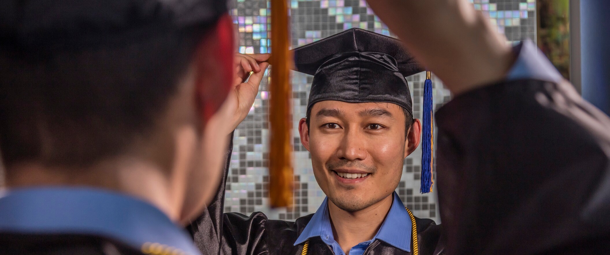 guy in graduation cap and gown looking in mirror